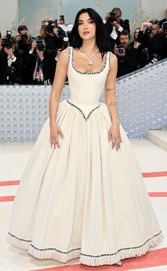 a woman in a white dress standing on a red carpet with cameras taking pictures behind her