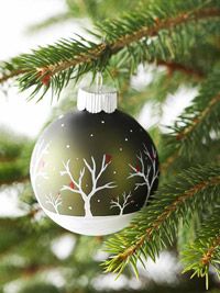 a green ornament hanging from a christmas tree with white and red designs on it