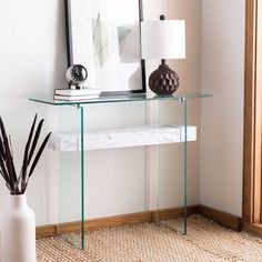 a white vase sitting on top of a glass table next to a mirror and lamp