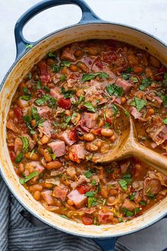 a pot filled with beans, ham and parsley on top of a blue towel