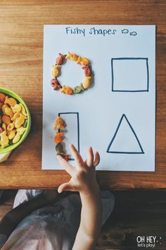 a child's hand on a piece of paper next to a bowl of cereal