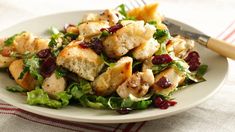 a salad with chicken, cranberries and lettuce on a white plate