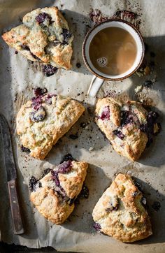 blueberry scones on parchment paper next to a cup of coffee