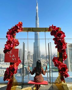 a woman is sitting on a swing overlooking the city