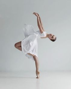 a woman in white is doing a dance pose with her arms extended and legs spread out