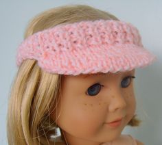 a doll with blonde hair wearing a pink knitted headband on top of her head