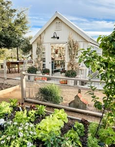 a small white house surrounded by lots of plants