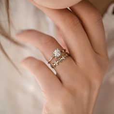 a woman's hand with a gold ring and two diamond rings on her fingers