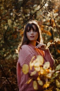 a woman standing in the woods with her hand on her shoulder and looking off into the distance