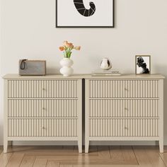 a white dresser sitting next to a wall with a framed picture on top of it