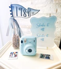 a blue camera sitting on top of a white table next to a vase filled with flowers