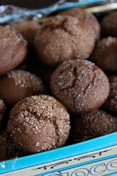 a blue box filled with chocolate cookies covered in powdered sugar on top of a table