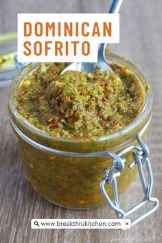 a jar filled with pesto sauce on top of a wooden table next to a spoon