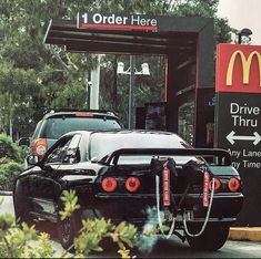 the back end of a black car parked in front of a mcdonald's drive thru