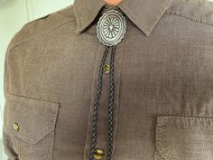 This awesome bolo tie handmade has a southwestern silver design. The cord is genuine black leather. Our bolos pair nicely with many of our belt buckles! They make wonderful gifts. The western bolo tie rope length is 40''. We can customize lengths and cord color, please ask! Western Style Concho Bolo Ties For Festivals, Vintage Brown Bolo Tie With Concho, Brown Bolo Ties As A Gift, Brown Bolo Tie For Gift, Black Western Bolo Tie With Concho, Western Brown Bolo Tie With Concho, Western Brown Bolo Ties With Concho, Western Black Bolo Ties For Western-themed Events, Adjustable Southwestern Bolo Tie