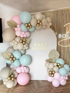 a baby shower backdrop with balloons and gold leaves on the top, in pastel colors