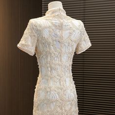 a white dress on display in front of a wall