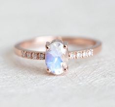 an oval shaped white opal and diamond engagement ring with rose cut diamonds on the side