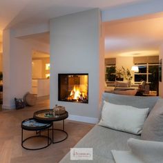 a living room filled with furniture and a fire place in the middle of it's wall