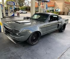 an old mustang is parked at a gas station