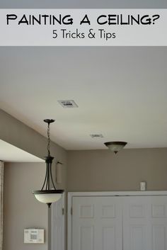 a room with a ceiling fan, light fixture and door to the other side that says painting a ceiling? 5 tricks & tips