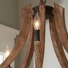 a wooden chandelier with two lights hanging from it's sides and wood strips on the bottom