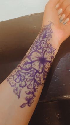 a woman's arm with purple flowers on it and her hand resting on the table