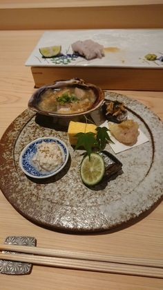 an assortment of food on a plate with chopsticks