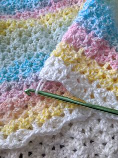 a crocheted blanket with a green knitting needle