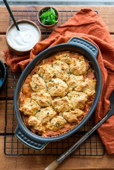 a casserole dish with meat and vegetables in it on a cooling rack next to a bowl of ranch dressing