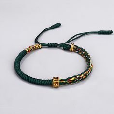 a green string bracelet with two gold clasps and beads on it's end