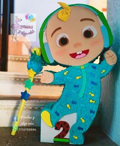 a stuffed toy doll holding a star on top of a wooden block in front of a door