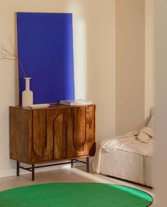 a living room with a green rug and a blue painting on the wall behind it