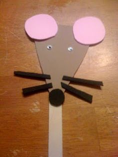 a mouse made out of popsicle sticks on top of a wooden table with pink eyes