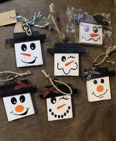 four snowmen made out of paper bags sitting on top of a table next to some string