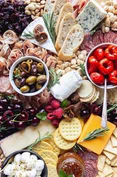 a wooden platter filled with cheese, crackers and olives