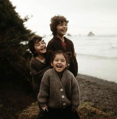 three young children standing next to each other near the ocean