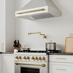 a stove top oven sitting inside of a kitchen next to a wooden cutting board and utensils