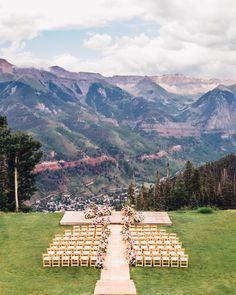 an outdoor ceremony set up in the mountains with chairs and flowers on each side,