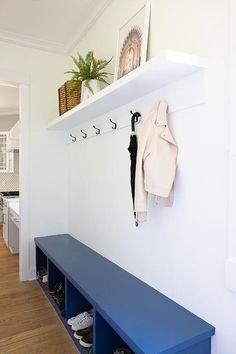 there is a coat rack and shoes on the wall in this entryway with blue benches