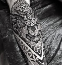 a man's arm with a skull and geometric patterns on it, in black and white