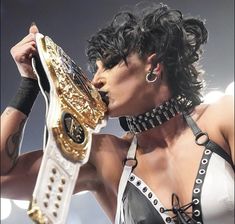 a woman with black hair is holding a gold and white wrestling belt in front of her face