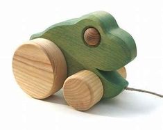 a wooden toy that looks like a green frog with wood wheels on the front and sides