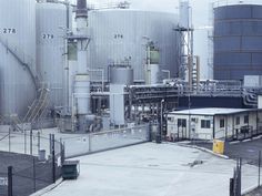 an industrial area with several large tanks in the back ground and one building on the other side