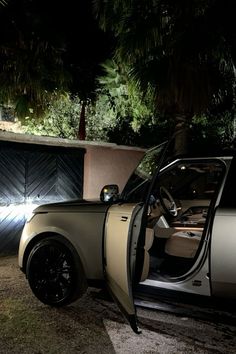 a car parked in front of a house at night with its door open and it's lights on