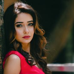 a woman in a red dress leaning against a wall