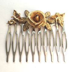 This listing is for a silver toned hair comb adorned with a vintage gold toned rose jewelry piece. 2 gold toned cherubs on each side. The comb is 2 inches wide. Costume jewelry.  Please visit my shop for more hair combs with vintage jewelry and unique jewelry! I combine shipping. First Class packages will be shipped bubble wrapped inside of a padded envelope. Priority Mail packages will be shipped bubble wrapped in a box. Any displays not included in sale unless otherwise noted. Coin in photo for size reference. Feel free to reach out with any questions, thank you for visiting my shop! Toned Hair, Decorative Hair Combs, Bridal Accessory, Vintage Hair Combs, Vintage Rhinestone Brooch, Vintage Cameo, Sapphire Color, Rose Jewelry, Tone Hair