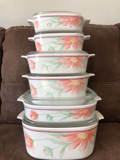 four ceramic casserole dishes stacked on top of each other with flowers painted on them