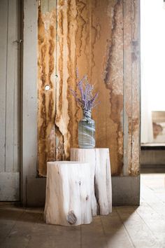 a vase with flowers sitting on top of a tree stump in front of a wall