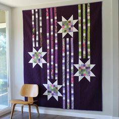 a chair sitting in front of a wall hanging quilt